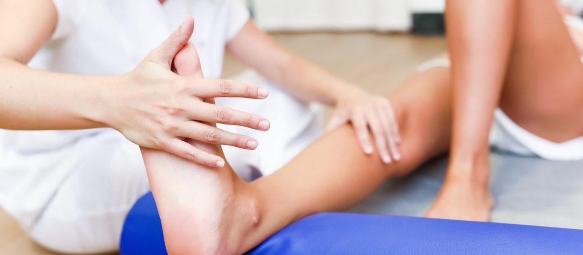 Female physiotherapist inspecting her patient. Medical check at the legs in a physiotherapy center.